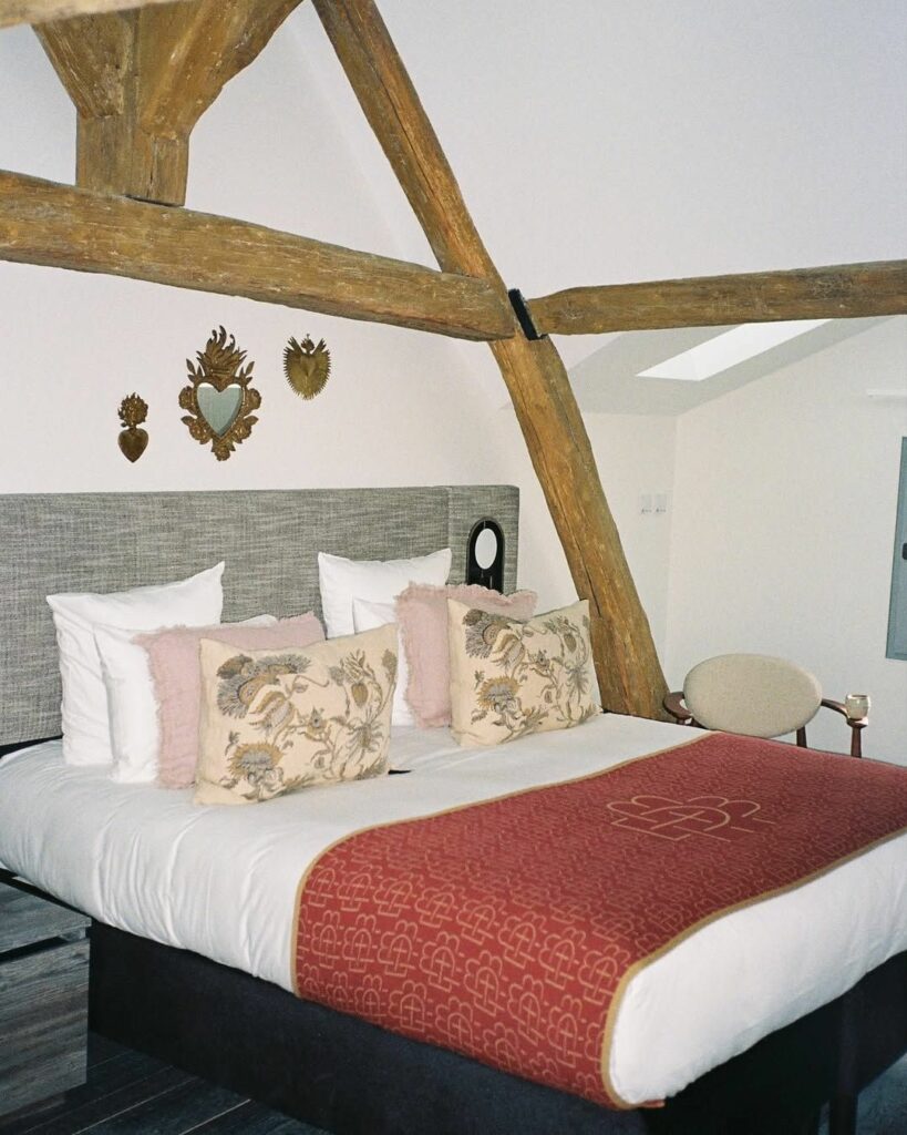 Plaid en maille sur mesure rouge et motif graphique disposé sur un lit dans une chambre de l’hôtel Boudoir des Muses