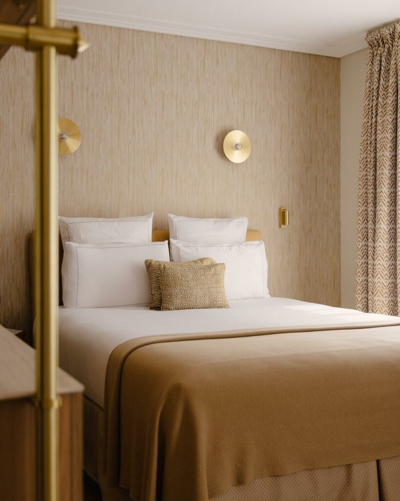 Chambre d’hôtel avec plaid en maille tweed beige posé sur le lit, ambiance chaleureuse et élégante à l’Hôtel Madison