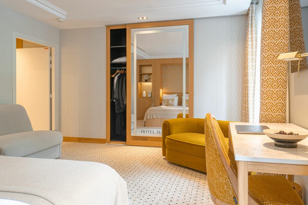Chambre d’hôtel avec mobilier en bois, fauteuils et lit avec textile haut de gamme