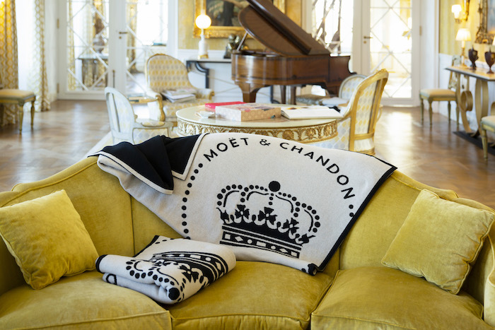Plaid en laine cachemire recyclé Moët & Chandon dans un salon élégant avec piano, projet textile pour l’hospitalité de luxe