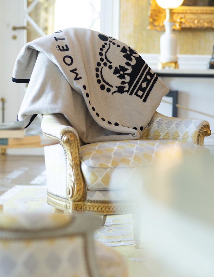 Plaid en laine cachemire recyclé Moët & Chandon posé sur un fauteuil, création textile responsable par La Maison de la Maille